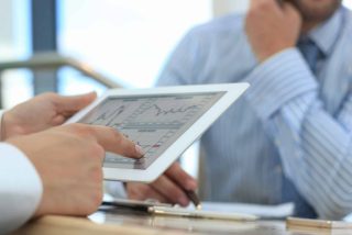 Image of human hand pointing at touchscreen in working environment at meeting